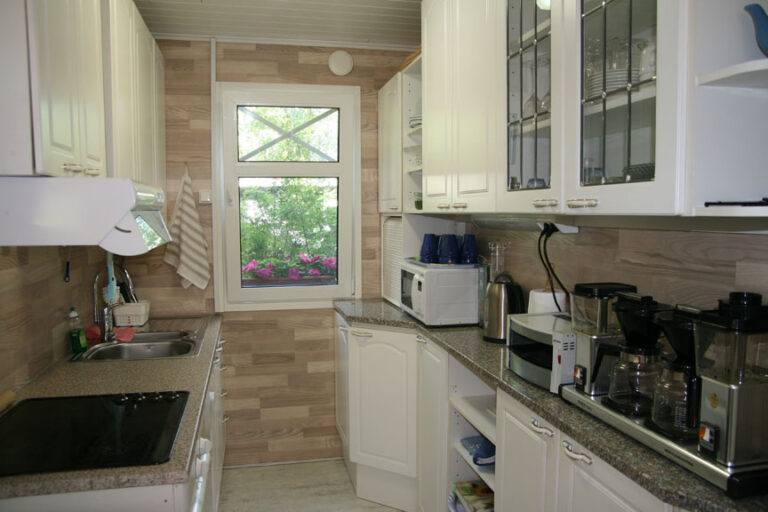 A bright kitchen with white cabinets and a window onto the yard.