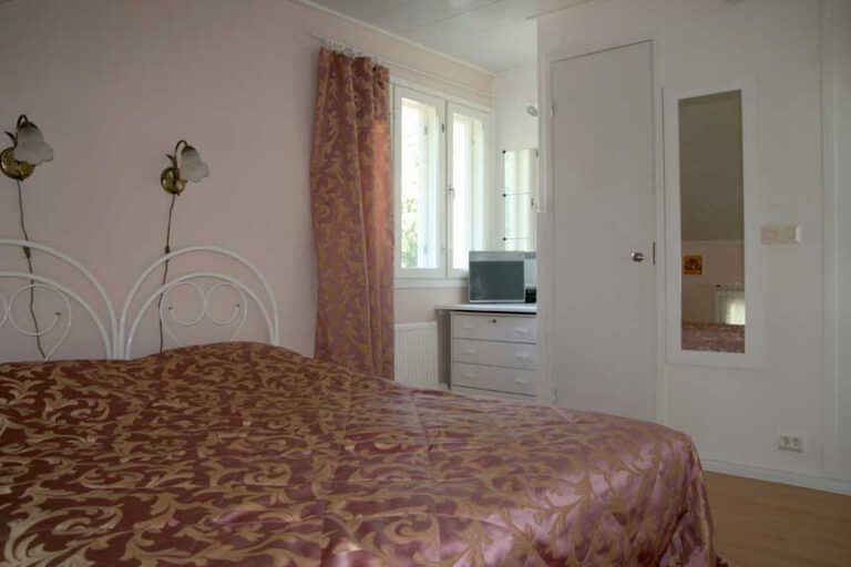 A bedroom with a double bed, a mirror and a window.